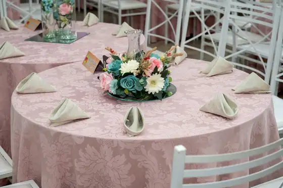 Mesa de convidados com toalha rosa e arranjo de flores