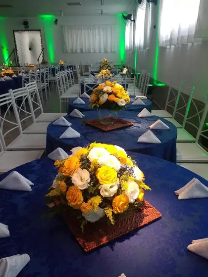 Mesas com toalhas azuis e arranjos de flores amarelas