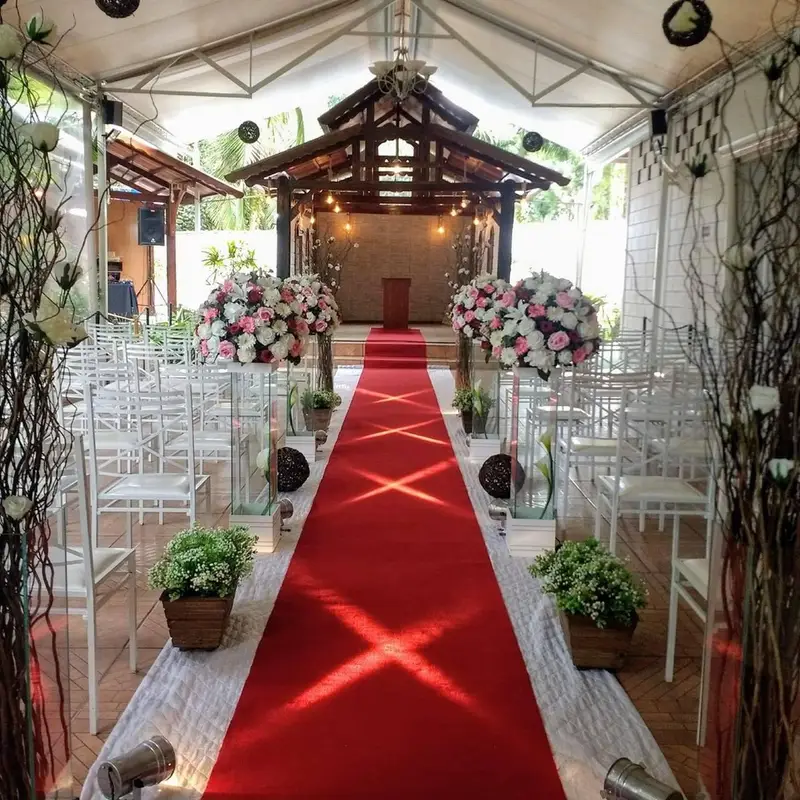 Área de cerimônia coberta com tapete vermelho e arranjos de flores