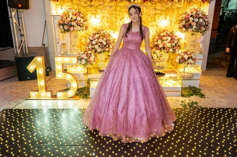 Debutante entre o número 15 iluminado e as flores