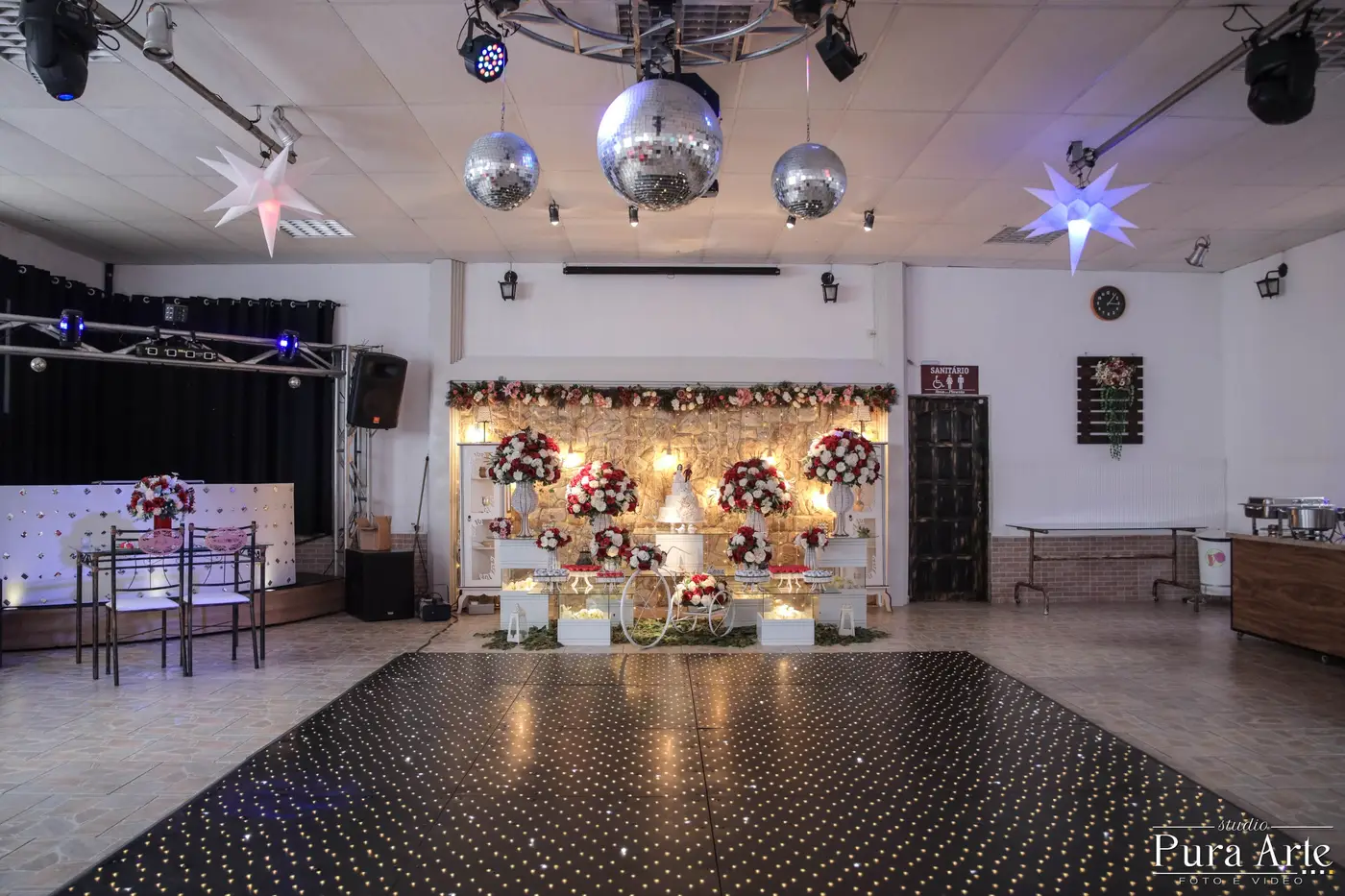 Salão de festa com a pista e a mesa do bolo ao fundo